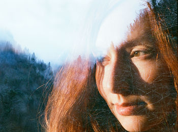 Double exposure of thoughtful woman and forest against clear sky