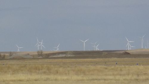 Wind turbines on field against clear sky