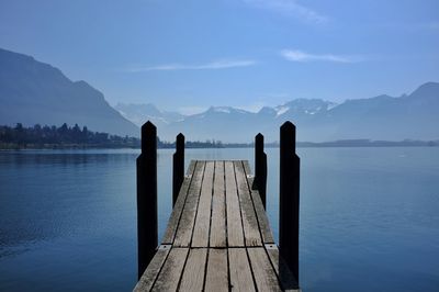 Wooden pier over lake against blue sky