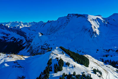 Scenic view of snow covered mountains against clear blue sky