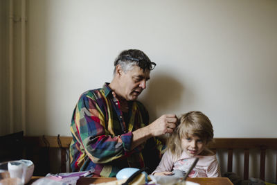 Grandfather helping granddaughter with her hair