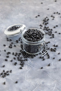 Glass jar full of dry black beans on grey table 