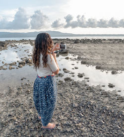 Woman standing at beach against sky