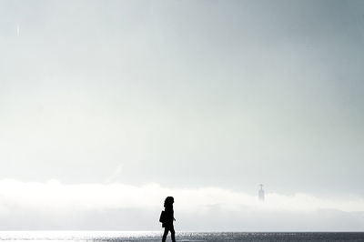 Silhouette man standing on beach against sky
