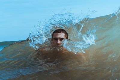 Young man swimming in splashing sea