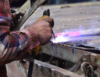 Cropped hands of male welder welding metal in factory
