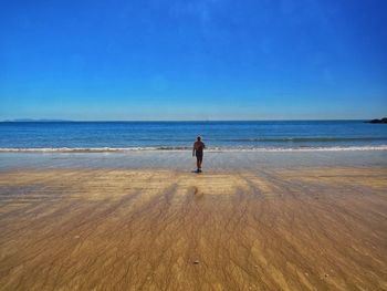 Rear view of woman on beach against sky