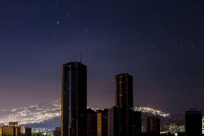 Illuminated buildings in city against sky at night