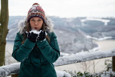 Portrait of young woman standing on railing