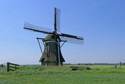 Traditional windmill on field against clear sky