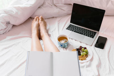 High angle view of woman using mobile phone on bed