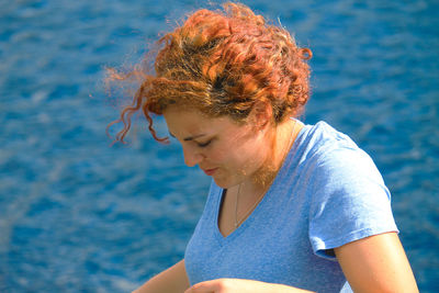 Woman looking down against sea at beach