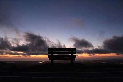 Silhouette built structure on landscape against sky at sunset