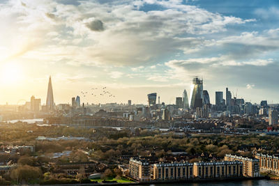 Aerial view of buildings in city against cloudy sky