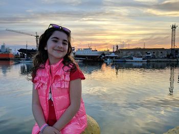 Portrait of smiling girl standing by pink against sky during sunset