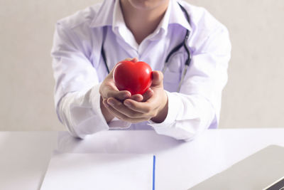 Midsection of man holding apple on table