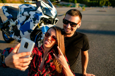 Young couple biker using mobile phone while standing on road