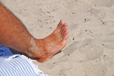 Low section of man on sand at beach