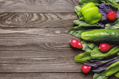 Fresh ingredients for salad - sorrel leaves, radishes, cucumber, sweet pepper on wooden background.