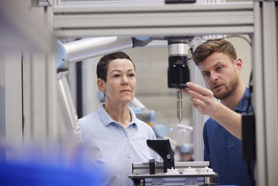 Technician explaining machine part to colleague in industry