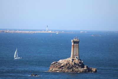 Lighthouse by sea against clear sky