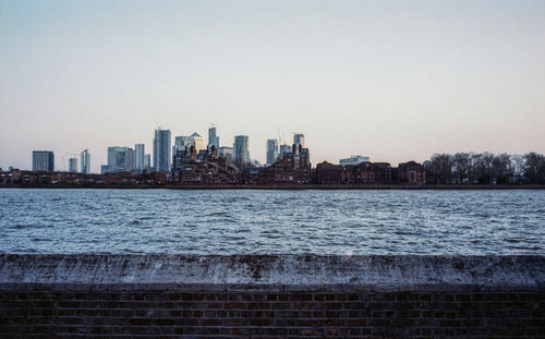 Sea by buildings against clear sky in city