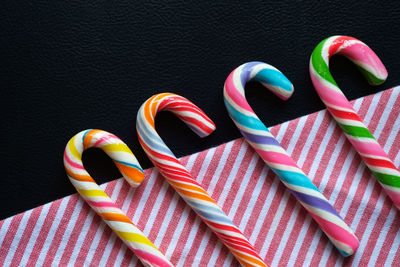 Close-up of candy canes on striped fabric against black background