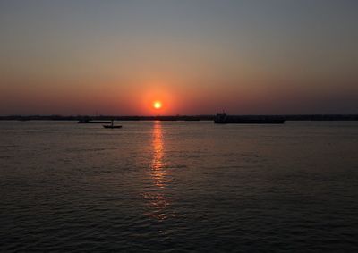 Silhouette boat sailing in sea against sky during sunset