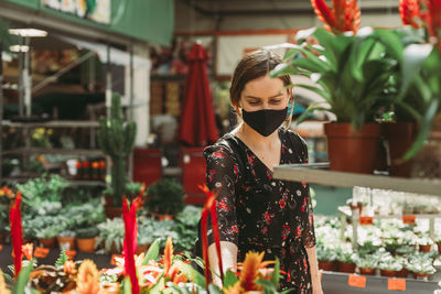 Portrait of woman standing by potted plants at store