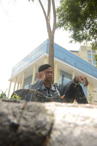 Low angle view of young man sitting on building