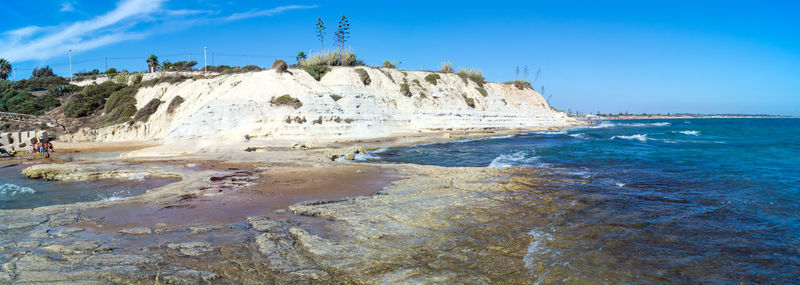 Rock formations on beach against blue sky