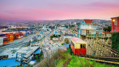 High angle view of railroad tracks by buildings against sky during sunset