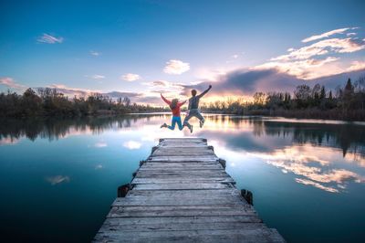 Man standing on pier over lake against sky