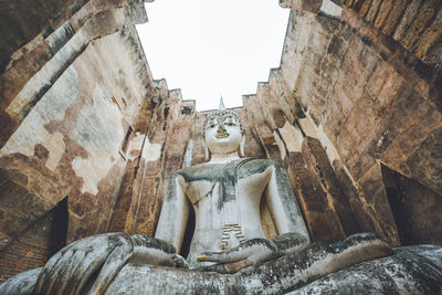 Statue of angel outside temple against buildings