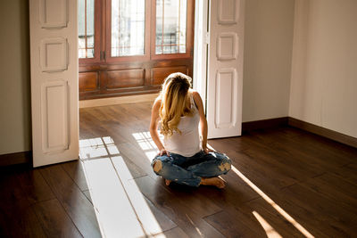 Anonymous pregnant female while sitting on floor in spacious room on sunny day