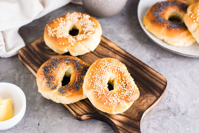 Bagels with poppy seeds and sesame on the board and butter in a bowl on the table