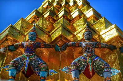 Low angle view of statues by wat phra kaew against clear sky