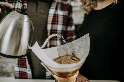 Couple prepares coffee by pouring hot water over grounds and filter