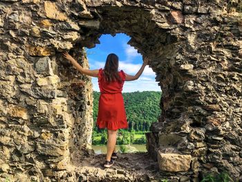 Woman in red dress surrounded by the ruins of an old fortress