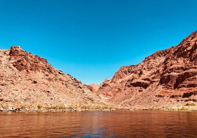 Scenic view of lake and mountains against clear blue sky