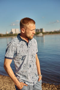 Young man looking at lake against sky