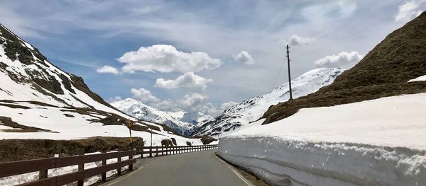 Road amidst snow covered mountains against sky