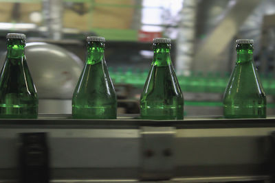 Automatic conveyer belt with green glass bottles for beverages. producing clean bottled water