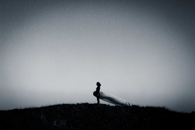 Silhouette woman standing on field against clear sky