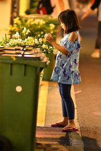 Side view full length of girl standing by garbage can at night