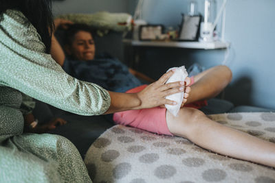 Caring mother putting ice pack on son's injured foot