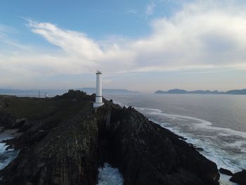 Lighthouse by sea against sky