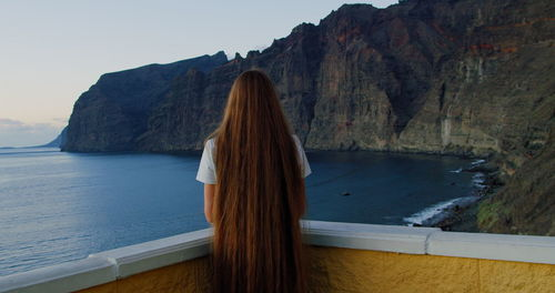 Ocean landscape and famous los gigantes cliffs on tenerife. rear view of woman.