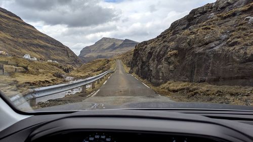 Road amidst mountains seen through car windshield