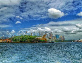 City at waterfront against cloudy sky